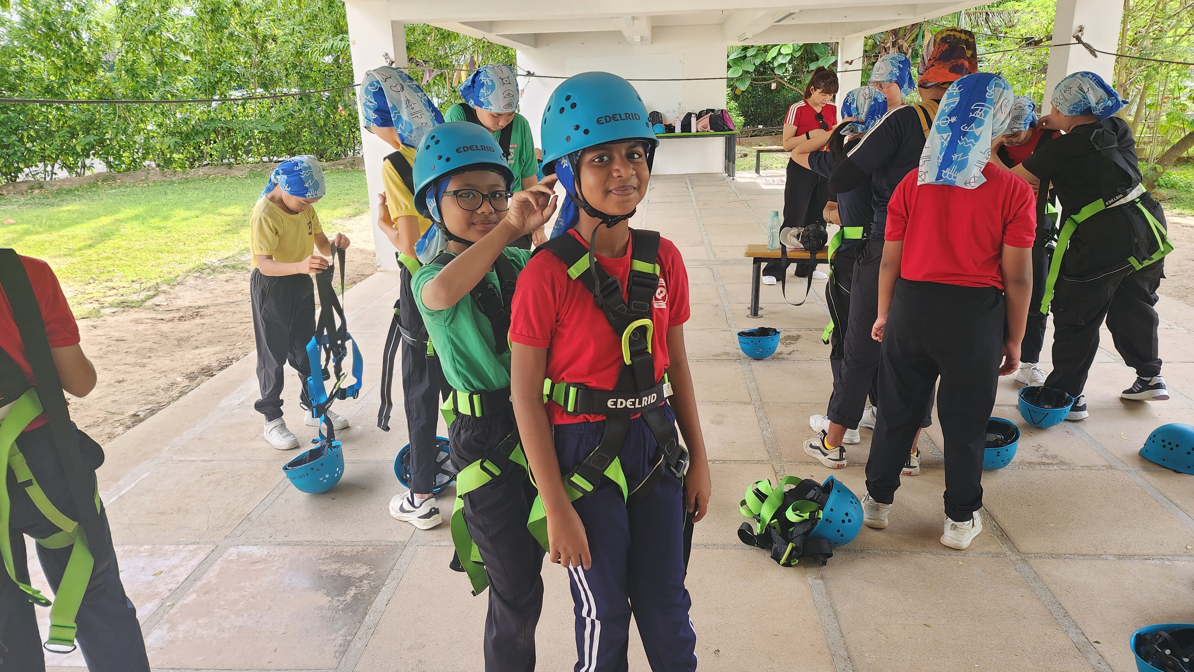 Students putting on their helmets and harnesses to get ready for abseiling and other high elements activities during P5 Outdoor Adventure Camp.